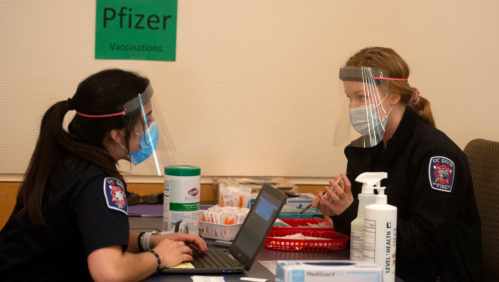 Students EMTs (in uniform) chat across table.