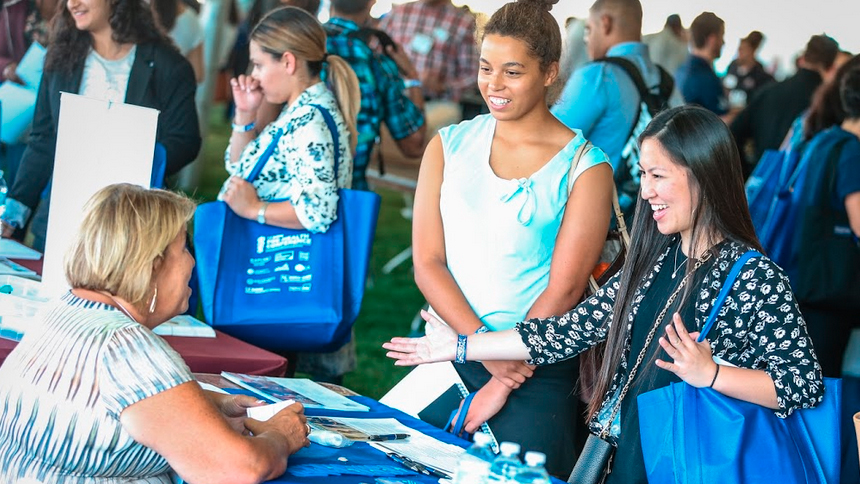 students visiting a conference booth