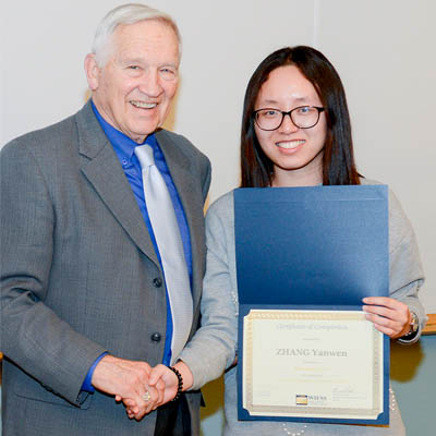 A young woman holds her certificate of completion