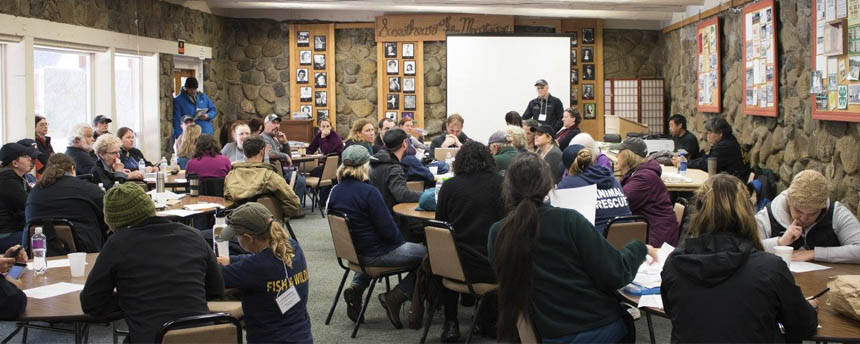 About forty people gather in a conference room to discuss oil spill drill logistics