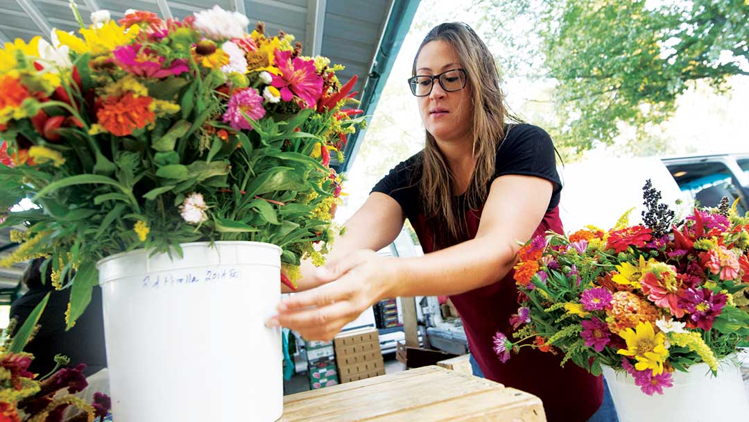 A woman arranges a bucket of flowers