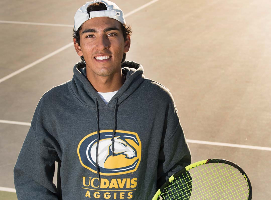 Chethan Swanson stands on a tennis court with a racket