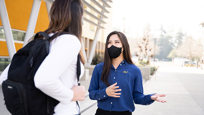 Jena Du on campus talking with a student