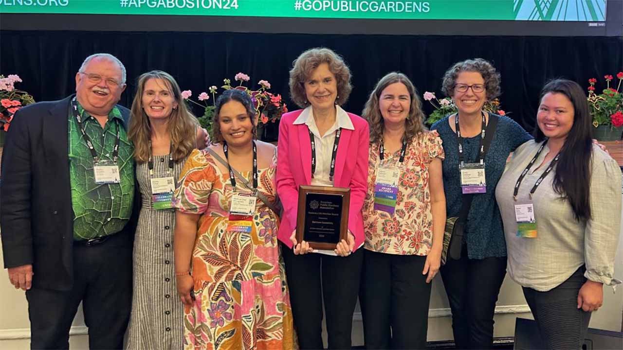 Group of people pose for photo at conference while holding award