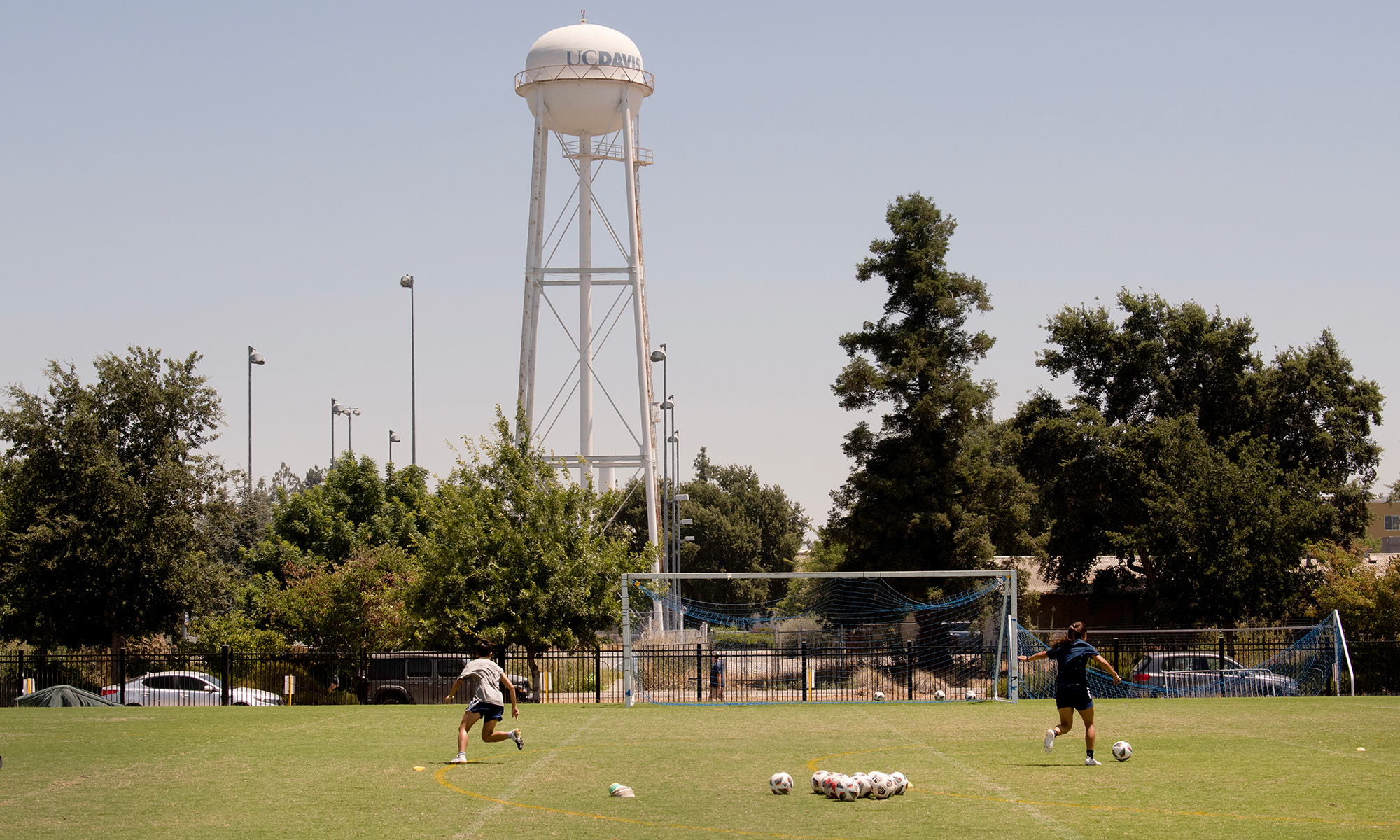 Soccer players on a field with a water tower in the background