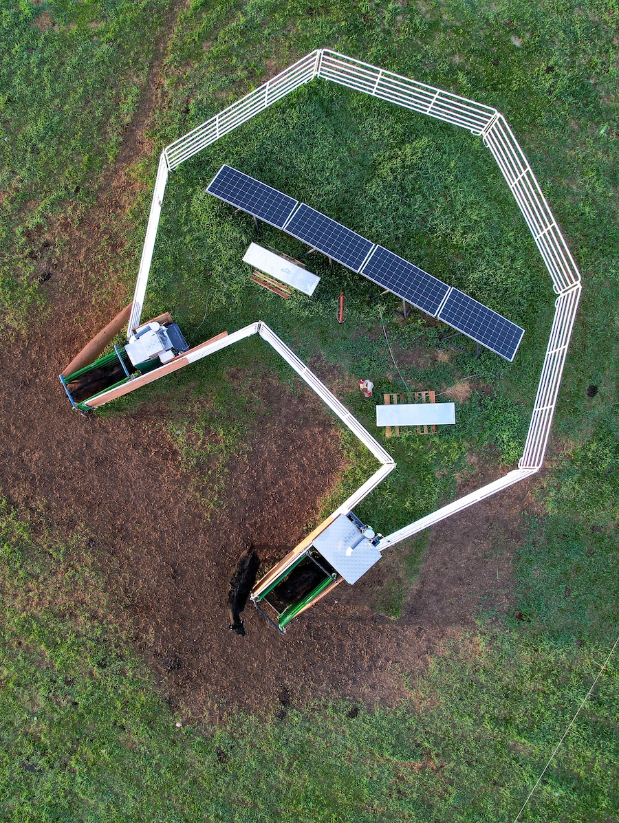 Overhead view of the machines that dispense the seaweed supplement, showing a white fence around solar panels. The solar panels power the machines. (Paulo de Méo Filho))