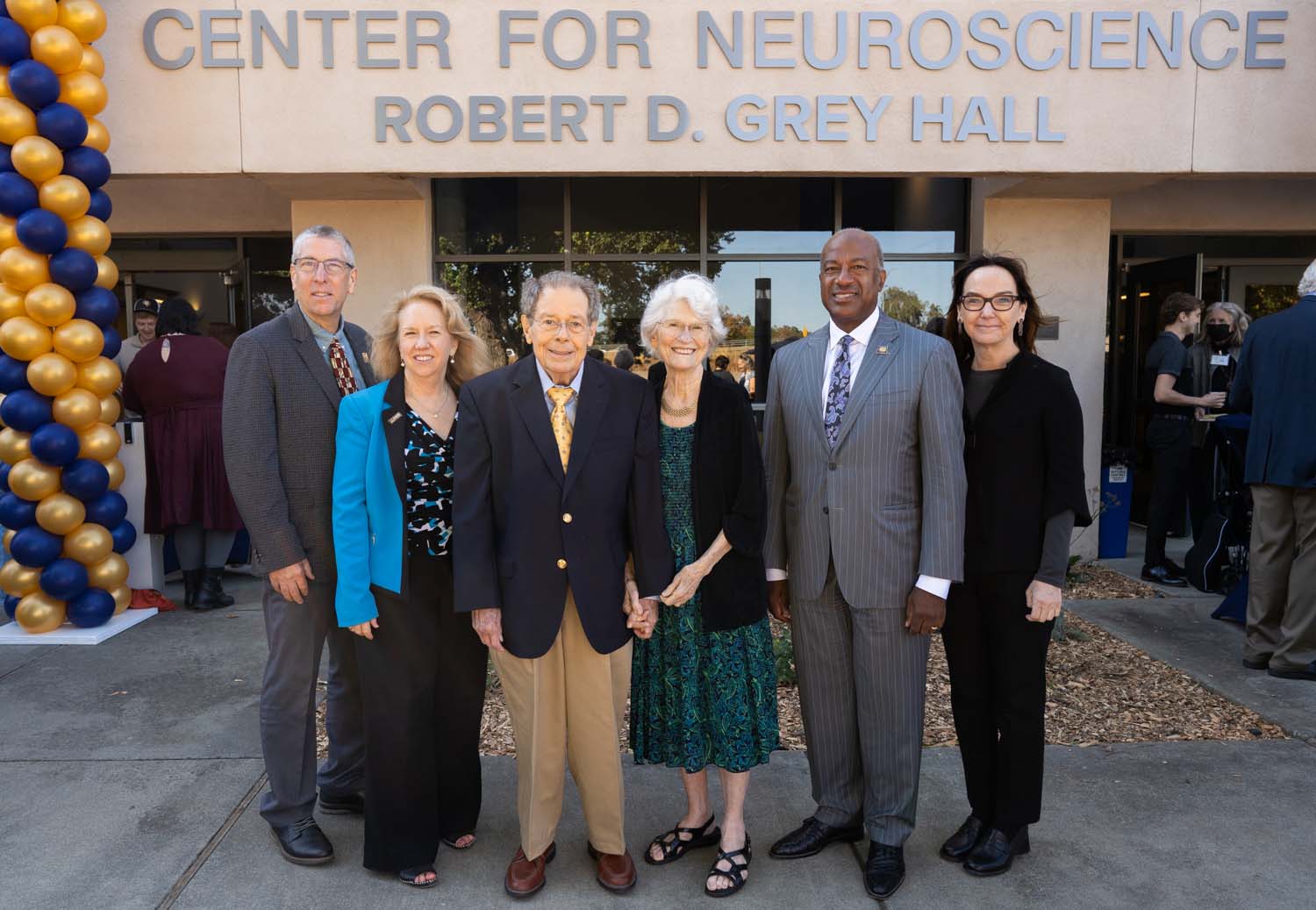 Group photo of six formally dressed people at Center for Neuroscience entrance