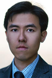 Formal headshot photograph of a man in suit and tie, neutral expression.
