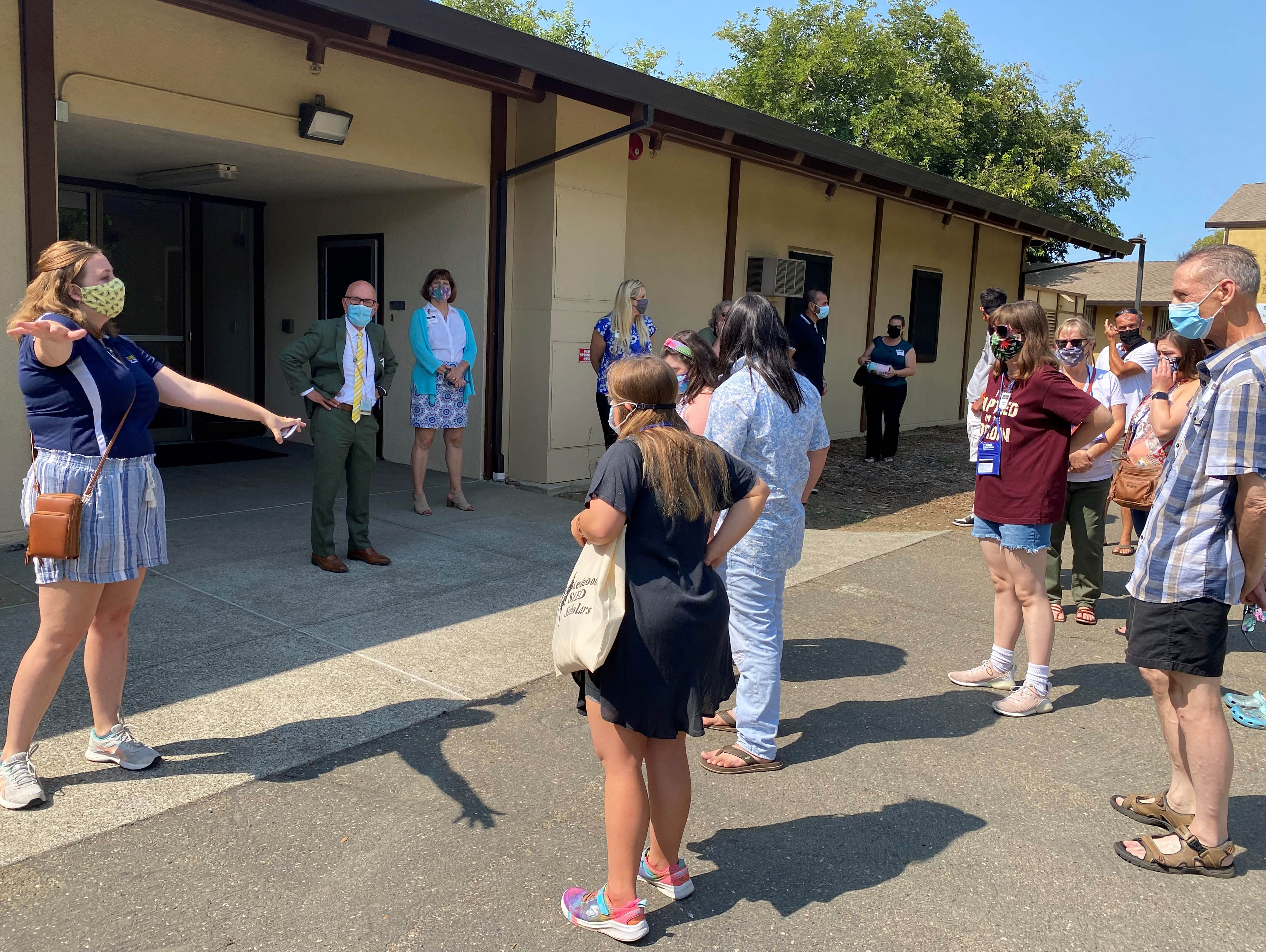 People stand outside of a building listening to a tour guide