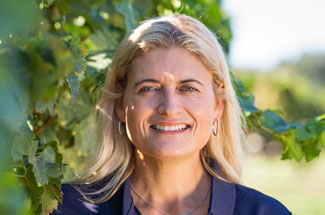 Woman poses with vineyard as backdrop