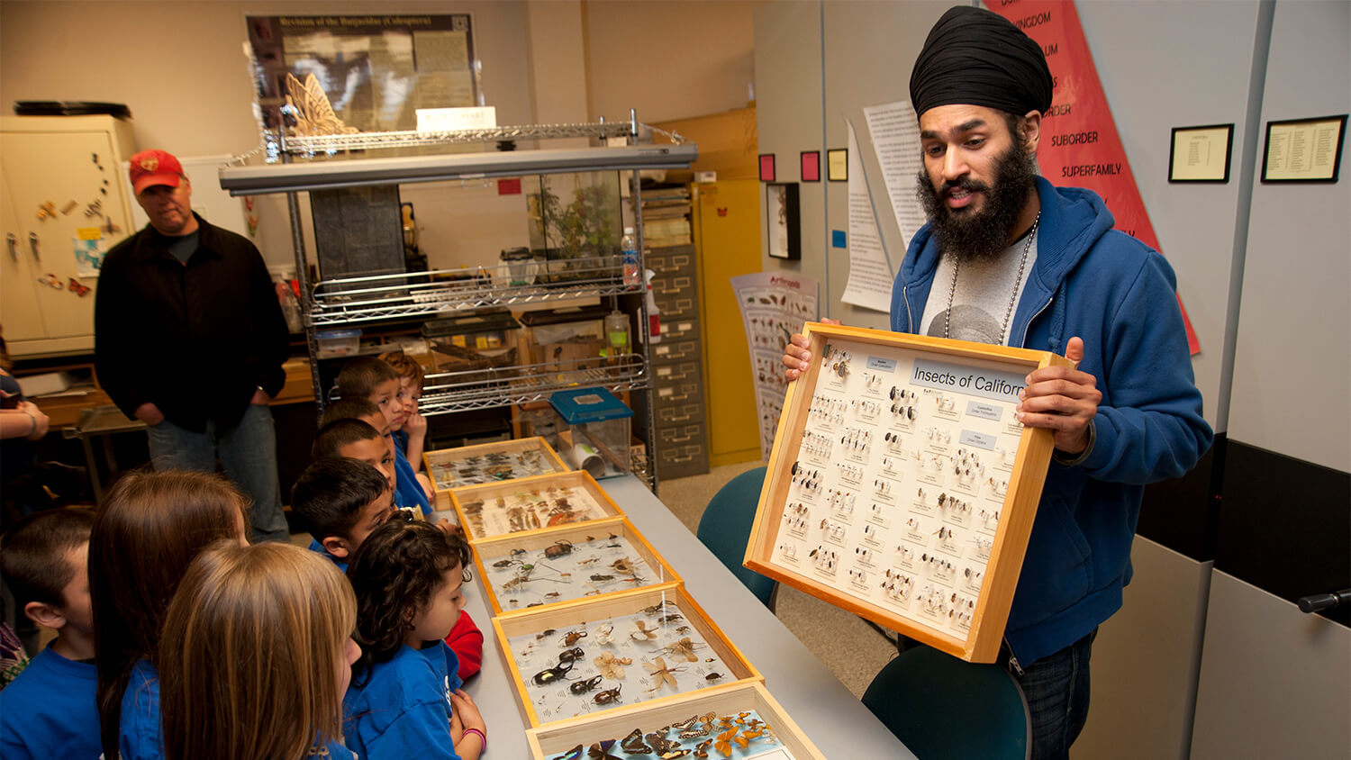 Jagveer Singh, a staff member, talks with elementary school children about California insects during a tour of the Bohart Museum of Entomology. 