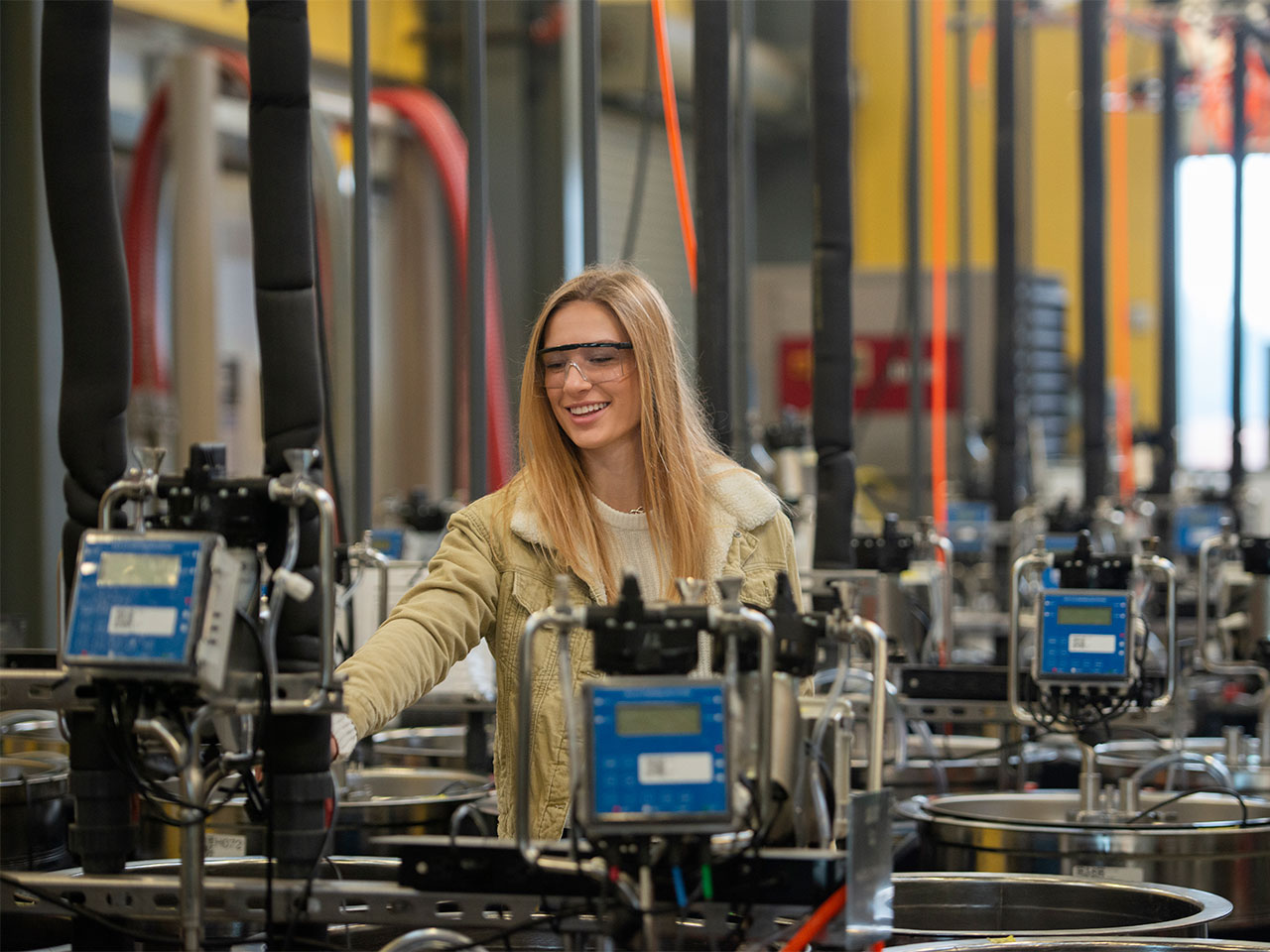 Nina Hodgonson, a viticulture major, poses with large wine vats while wearing protective goggles.