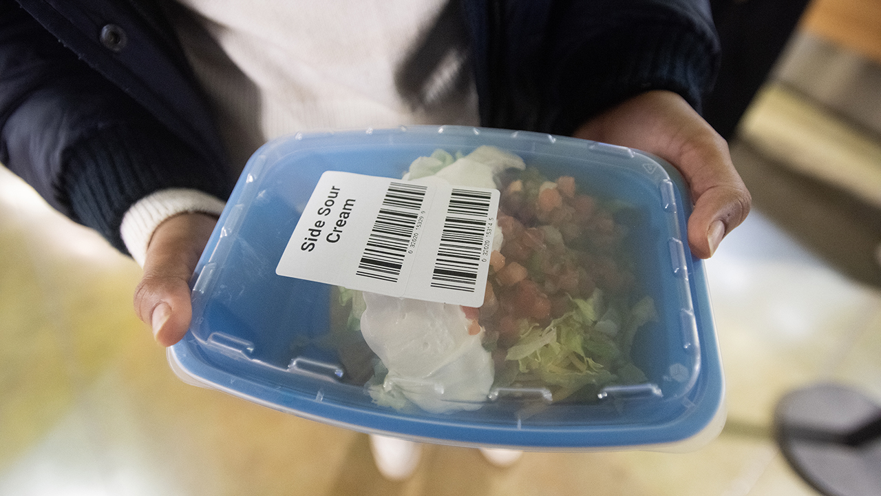 A closeup of a blue, reusable container with food in it and a transparent lid on it.