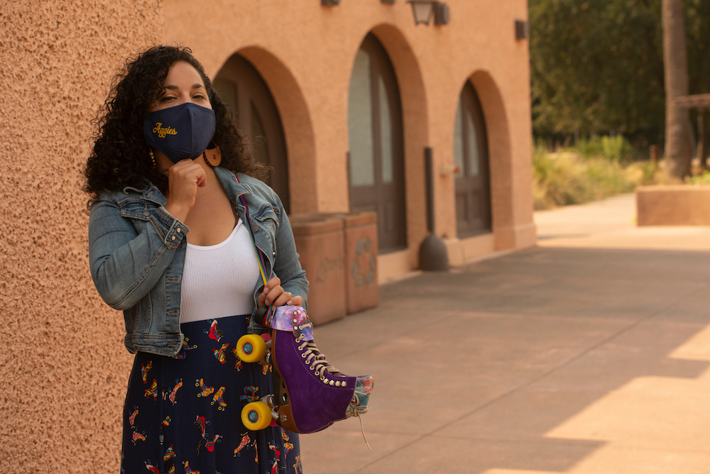 A student stands with rollerskates in her hand at the UC Davis train station.