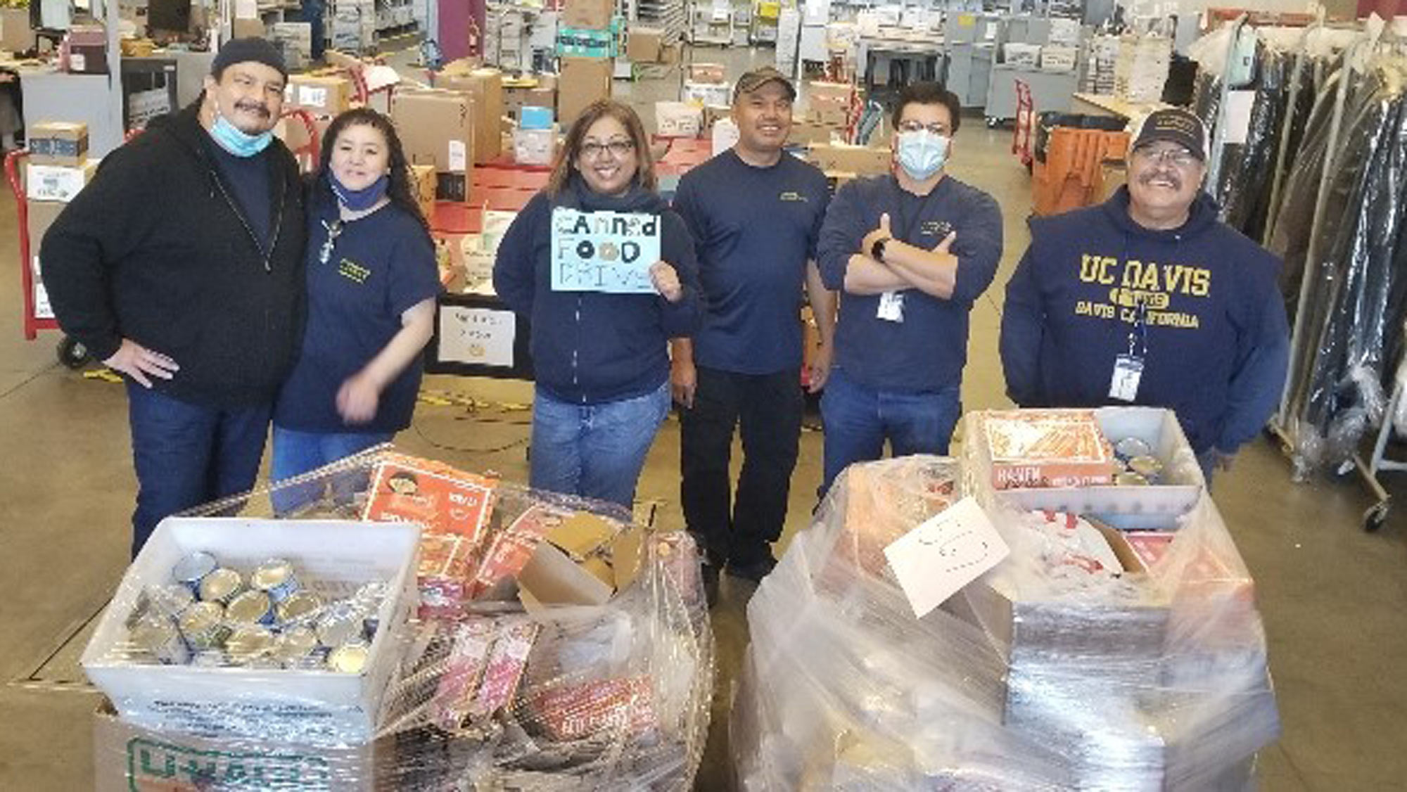 Mail Services personnel lined up behind pallets stacked with food.