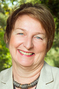 Smiling woman outdoors with short brown hair and beige blazer
