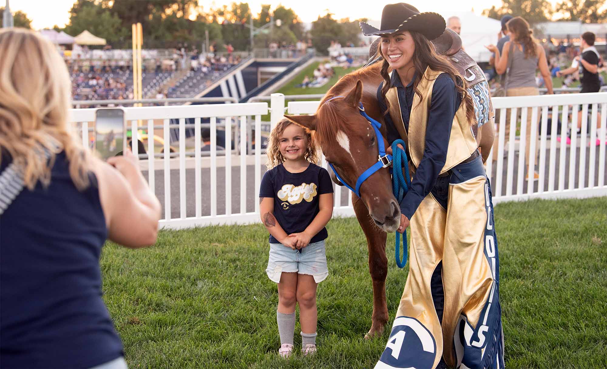 Student wearing Western regalia poses for photo with young child