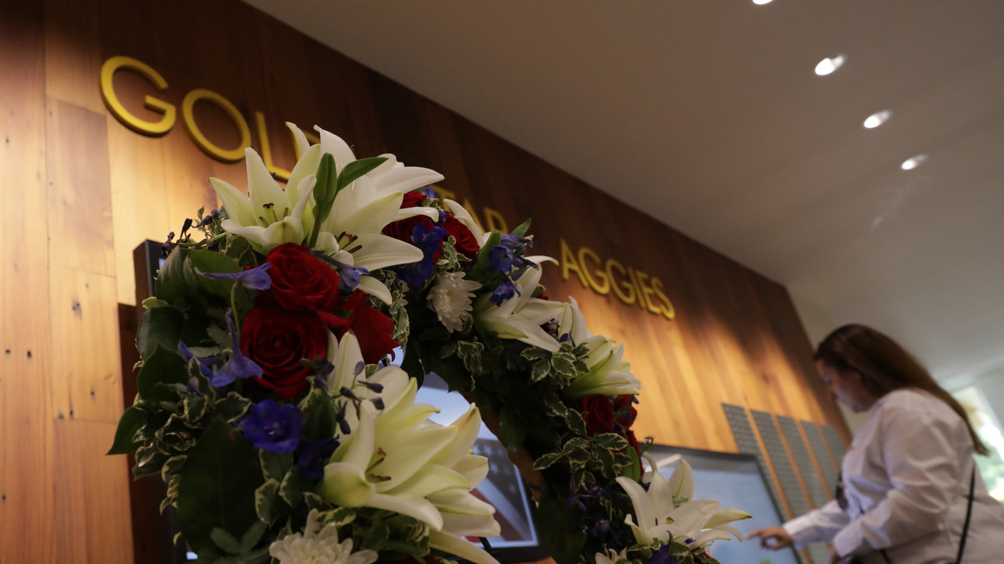 Gold Star aggies Wall with wreath and woman at touchscreen