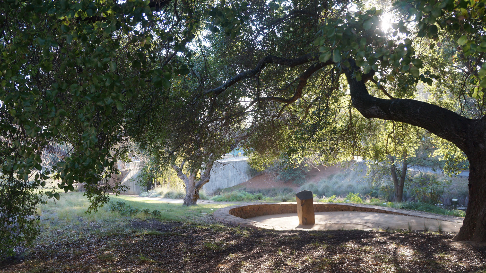 Circular seating area, made of rock, with granite monument in the middle