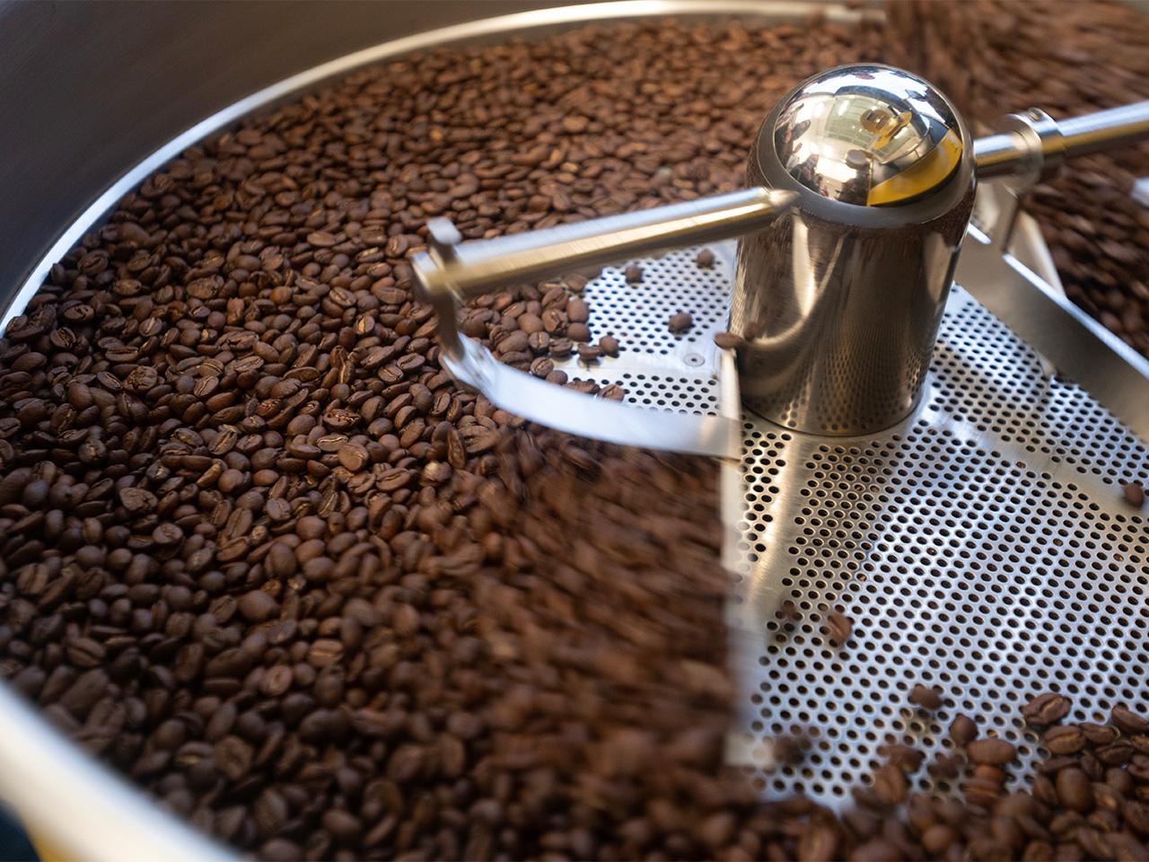 A closeup photo of coffee beans spinning on a roaster's cooling tray.