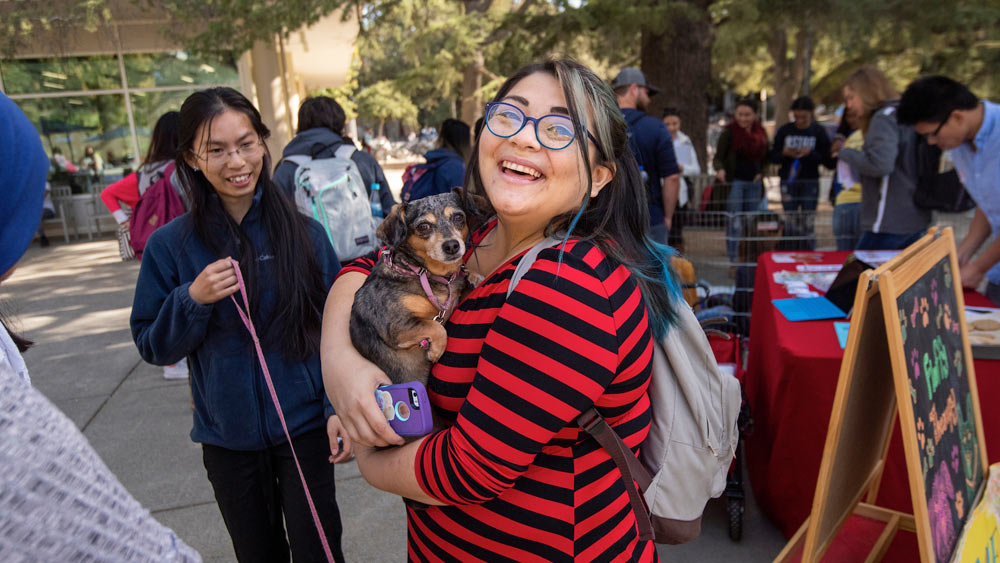 A female student cuddles with a puppy during finals week