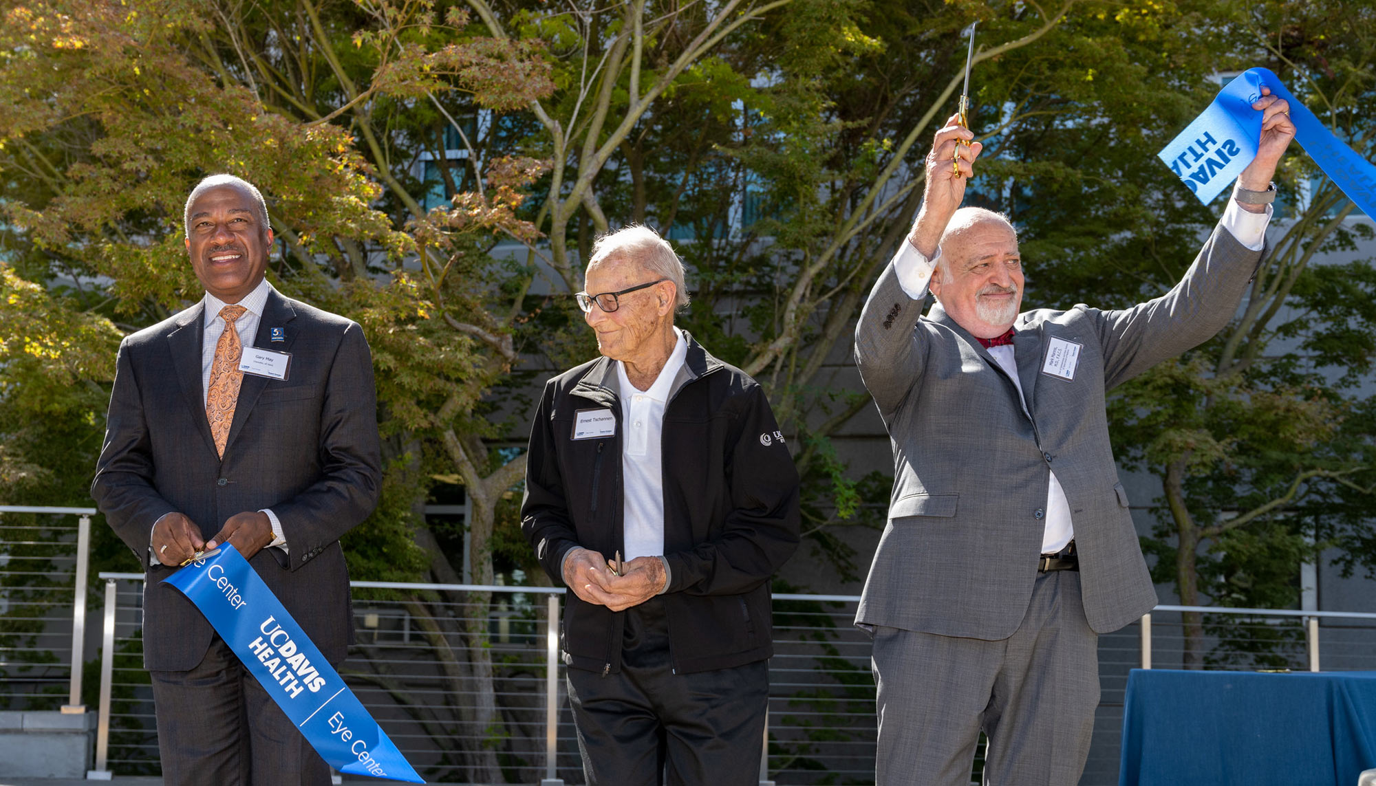 3 men, triumphant after ribbon-cutting