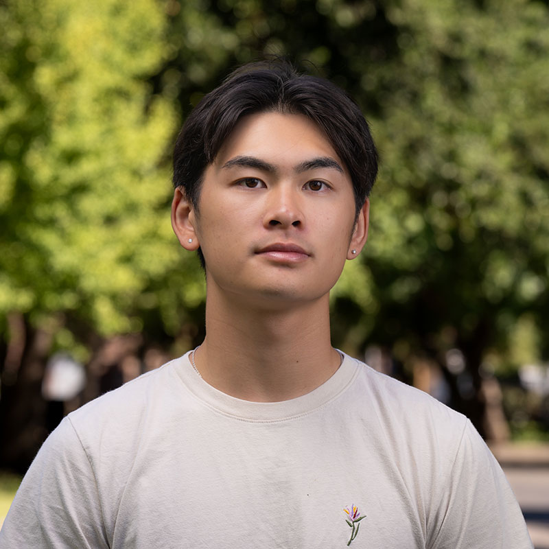 Portrait photo of a student wearing a white t-shirt and looking at the camera. They have black hair.