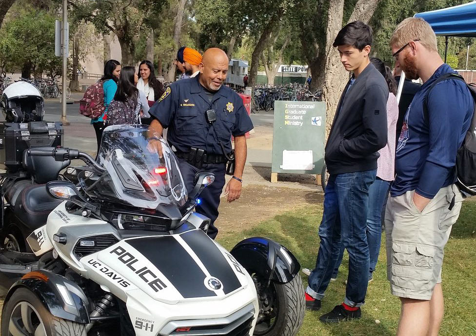 Police officer on the Quad, displaying three-wheel police cycle to students