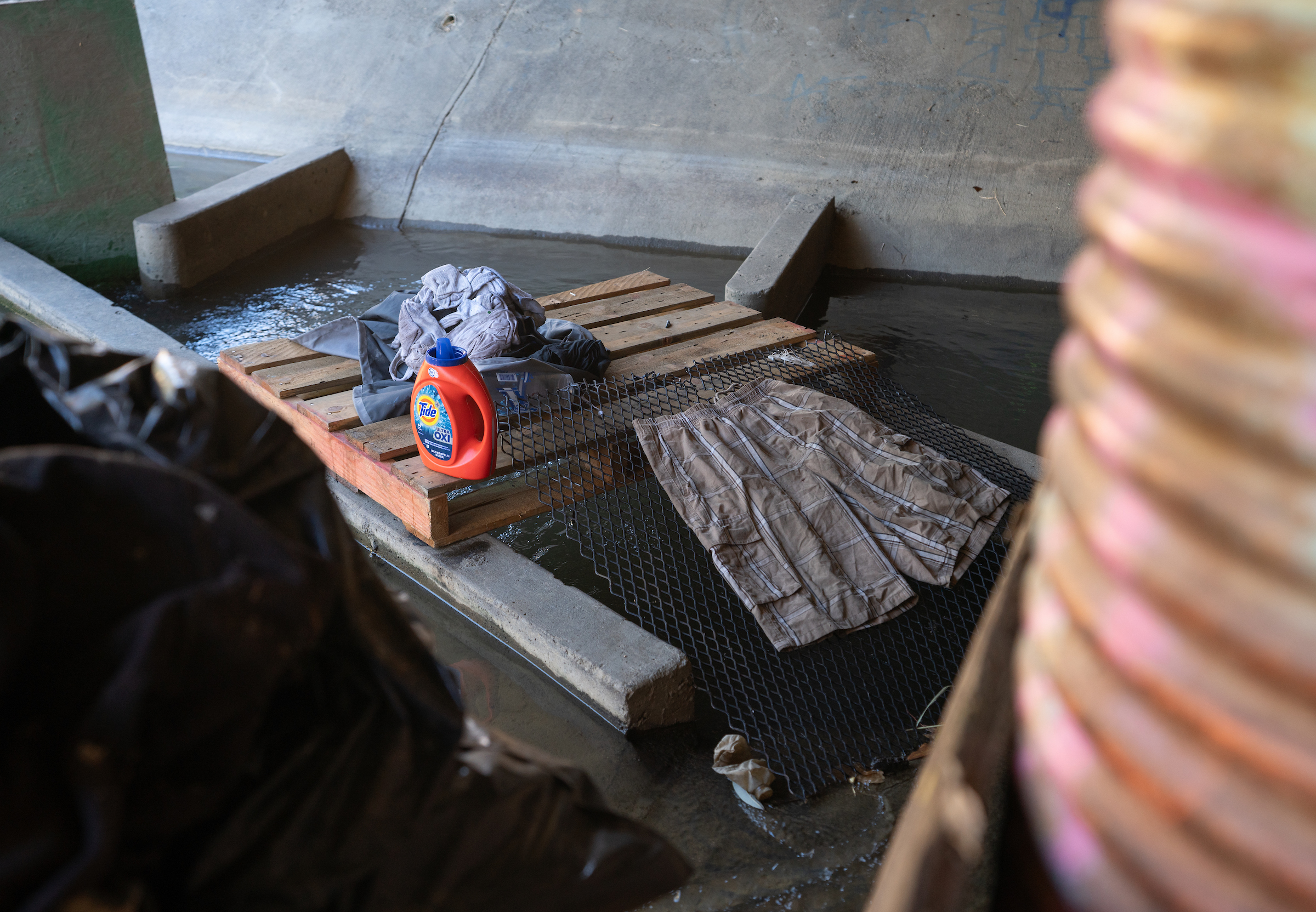 bright orange bottle of laundry detergent rests on wooden pallet in stream tunnel