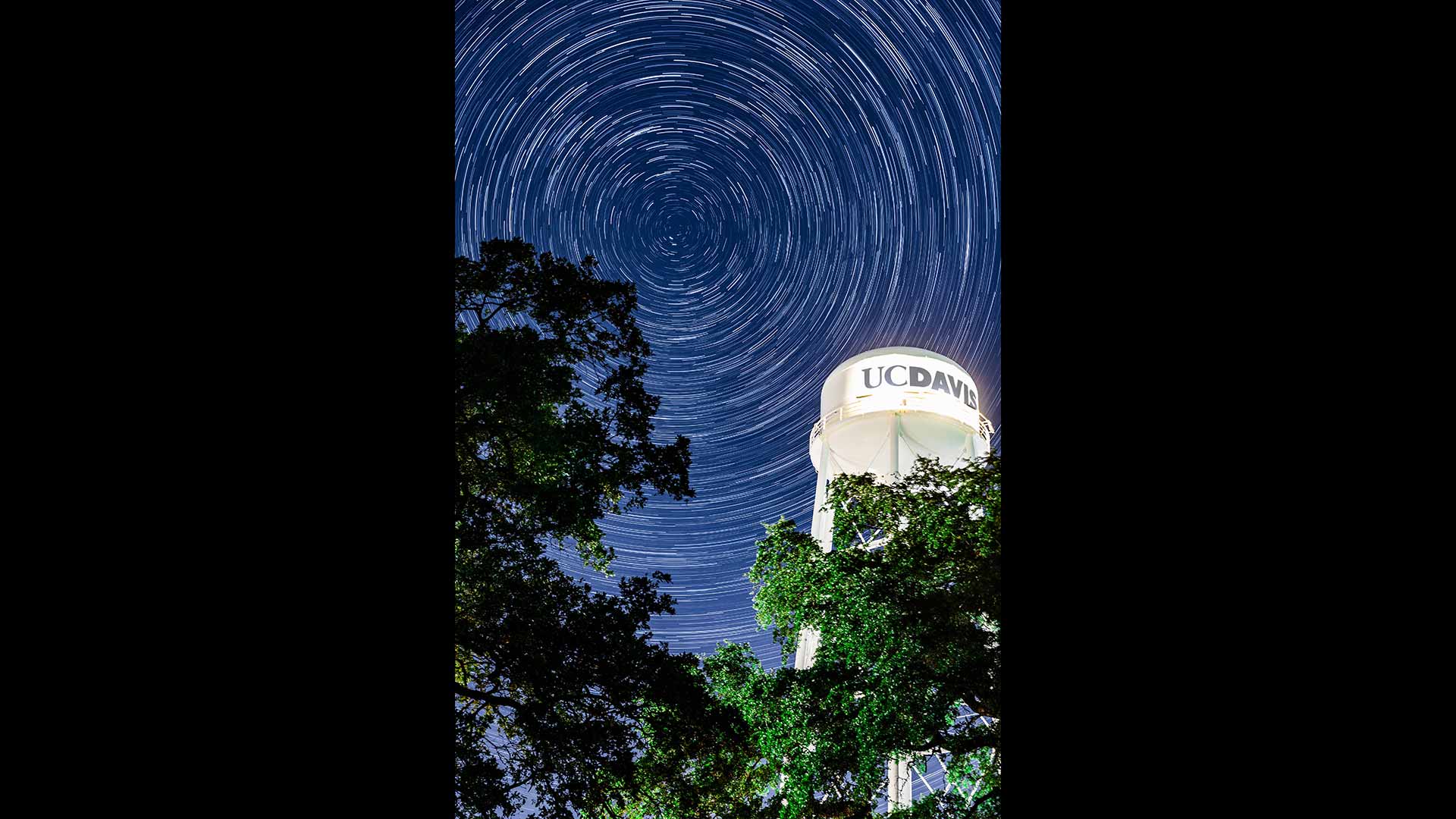 Composite photo of the stars in the night sky revolving near the top of a UC Davis water tower.