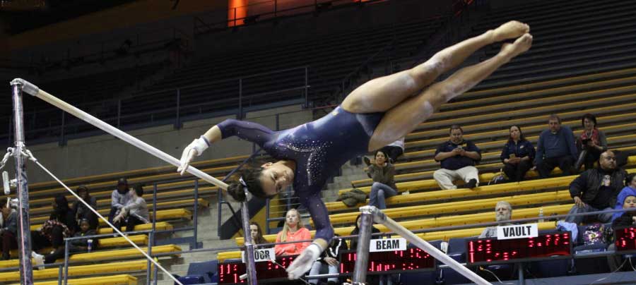 Alexis Brown in the air, while doing exercise on the uneven bars