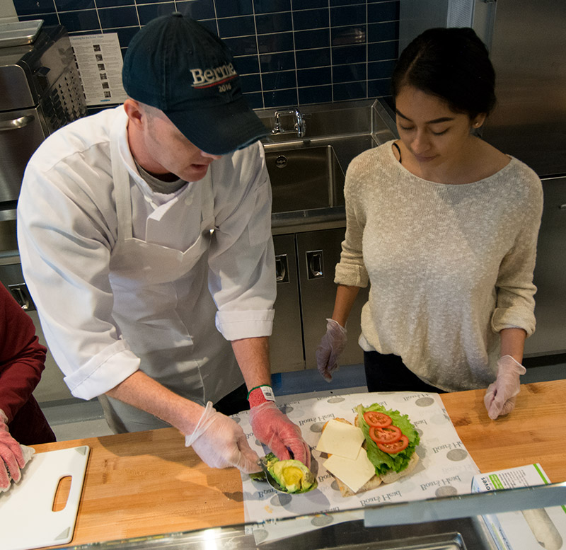 Cook shows student how to make a sandwich