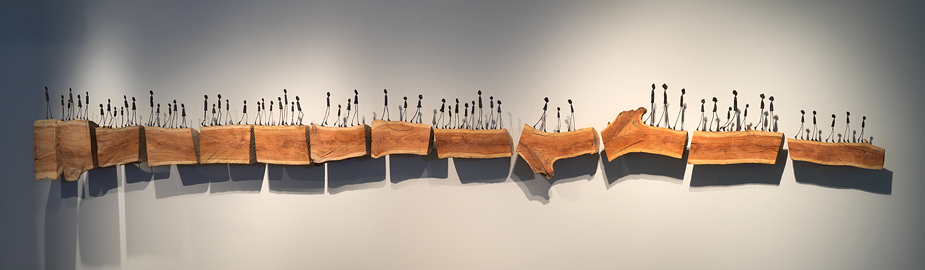 Bloodline sculpture, figures on wood platforms, as if walking across a wall