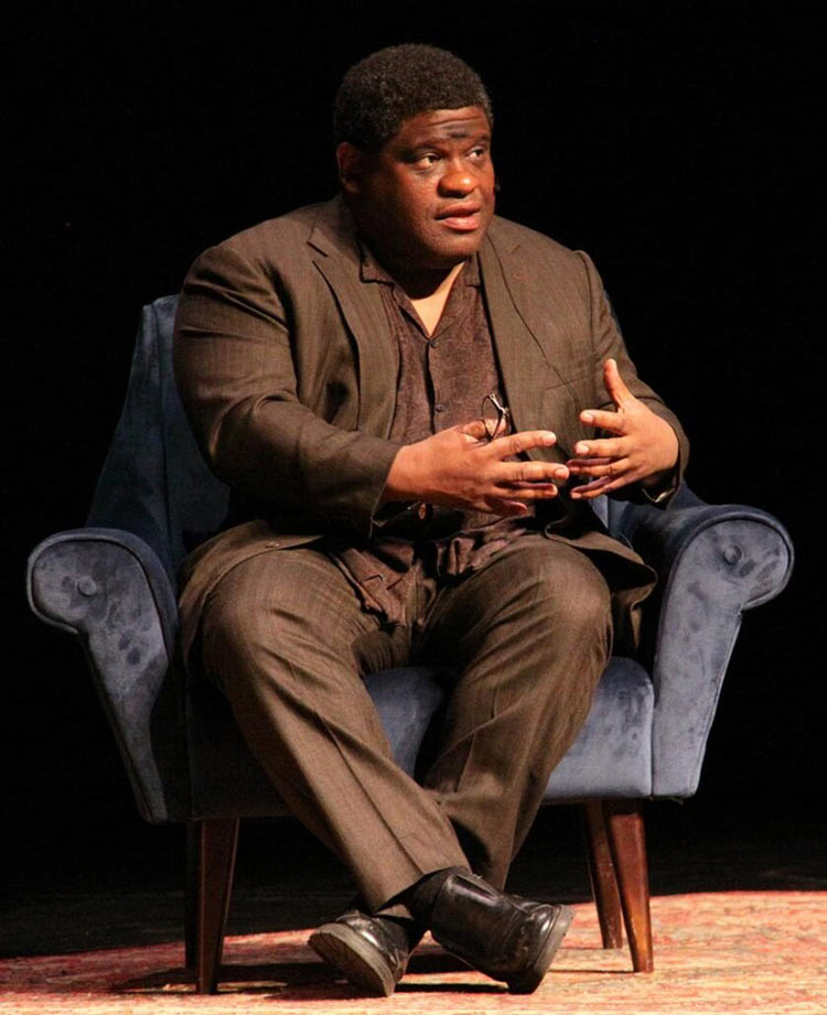 Author, in chair, on stage.