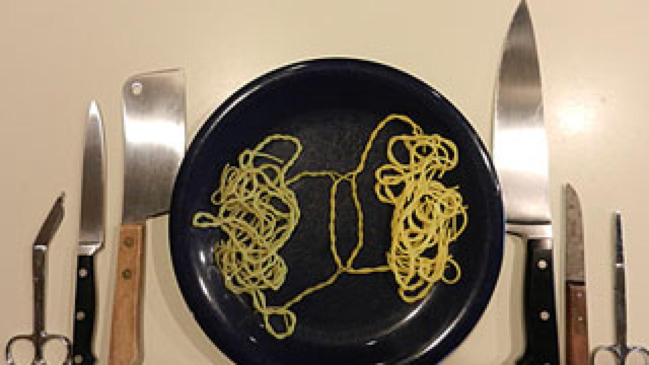 place setting with scissors, knives and a plate of spaghetti