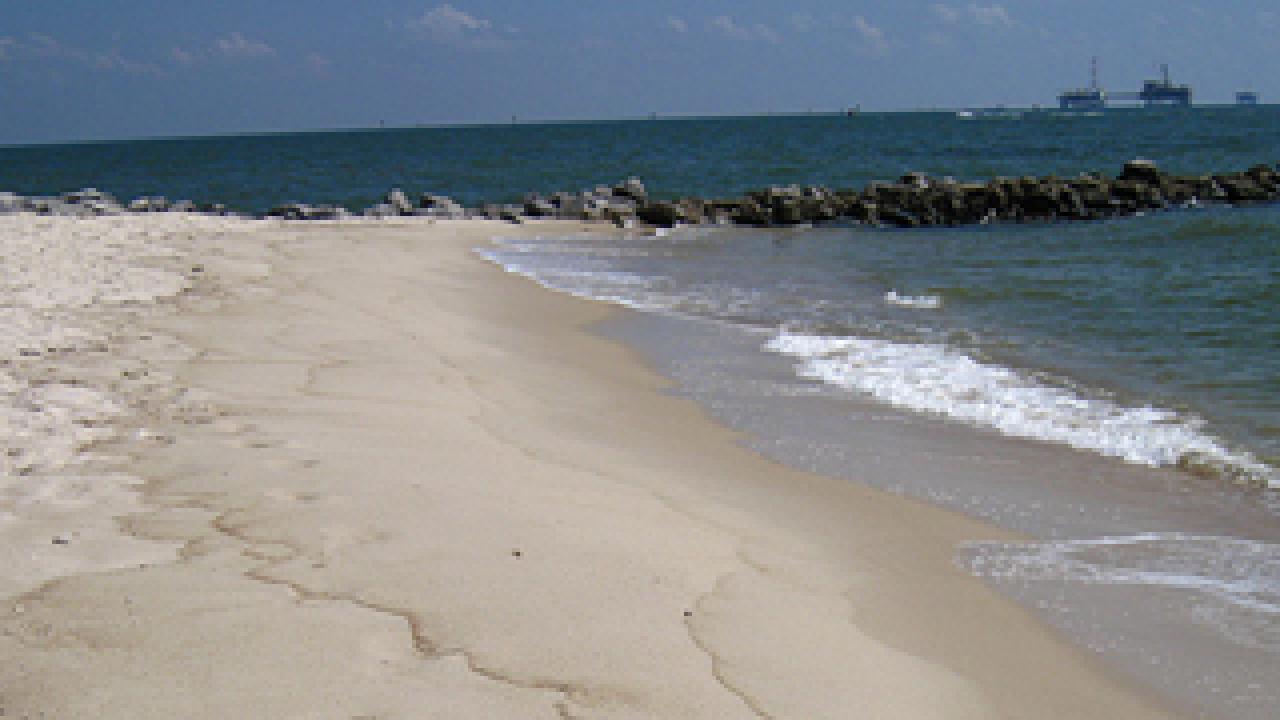 Beach and waves with platforms on the ocean in the background