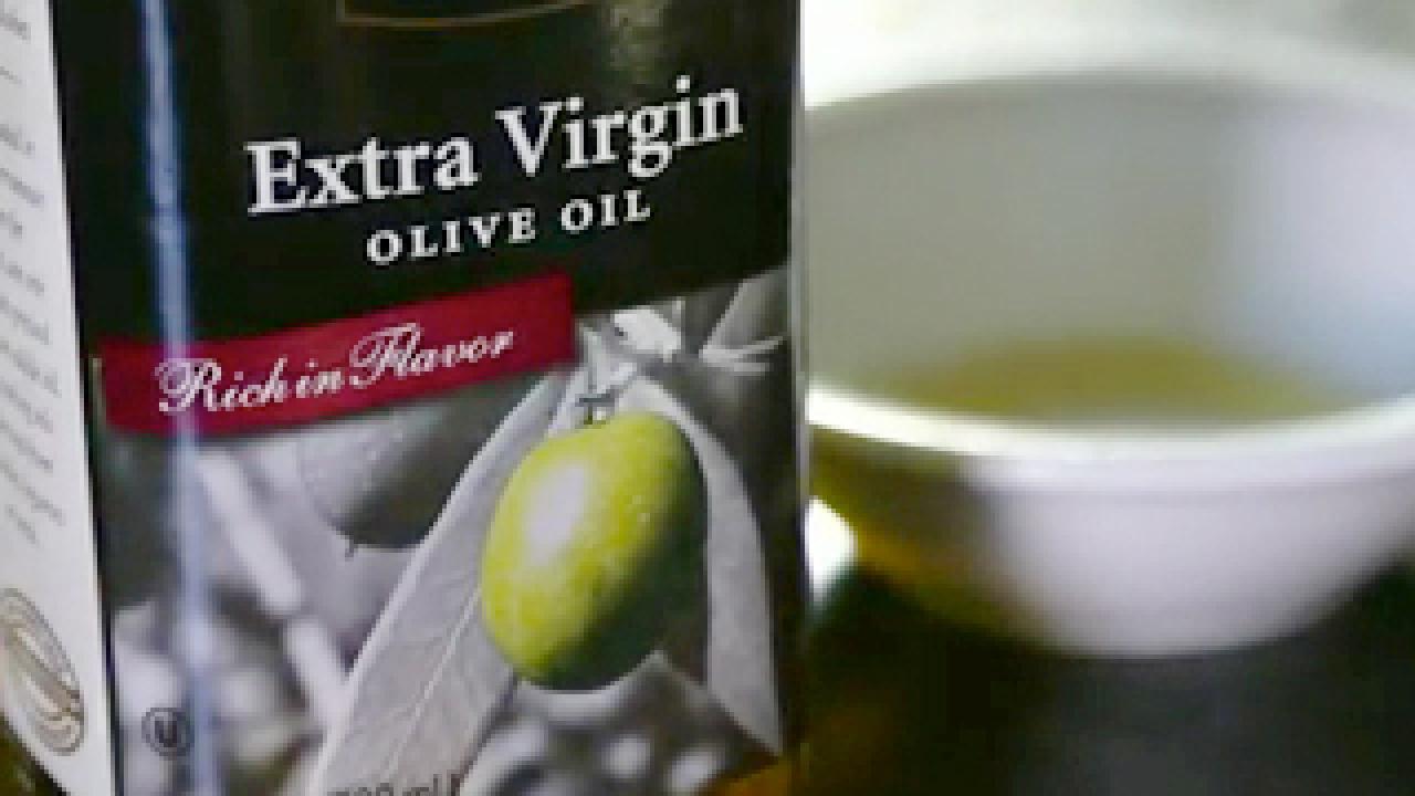 A bowl of olive oil with garnish of leaves and red berries