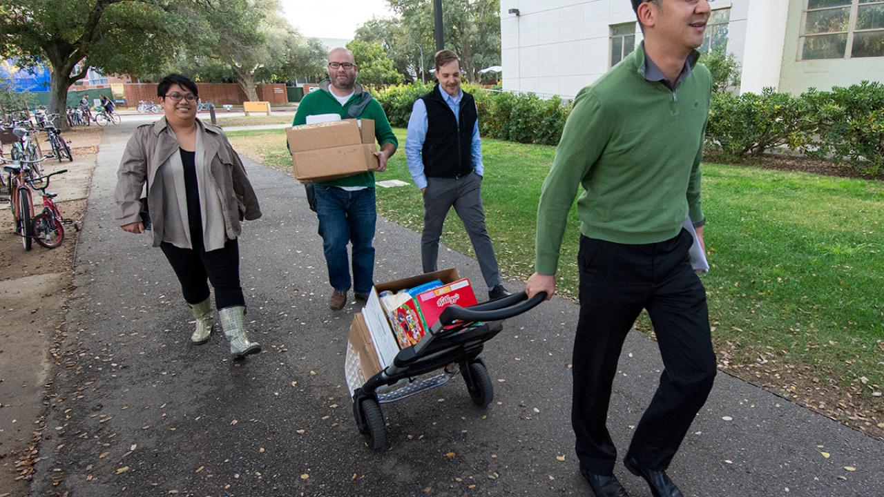 Employees carrying food and gifts to Justin Lok's car.