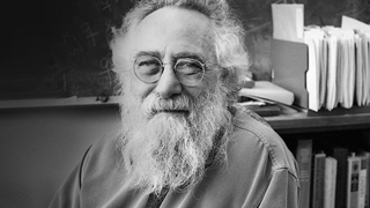 Michael Turelli in an office with a blackboard and books behind him.