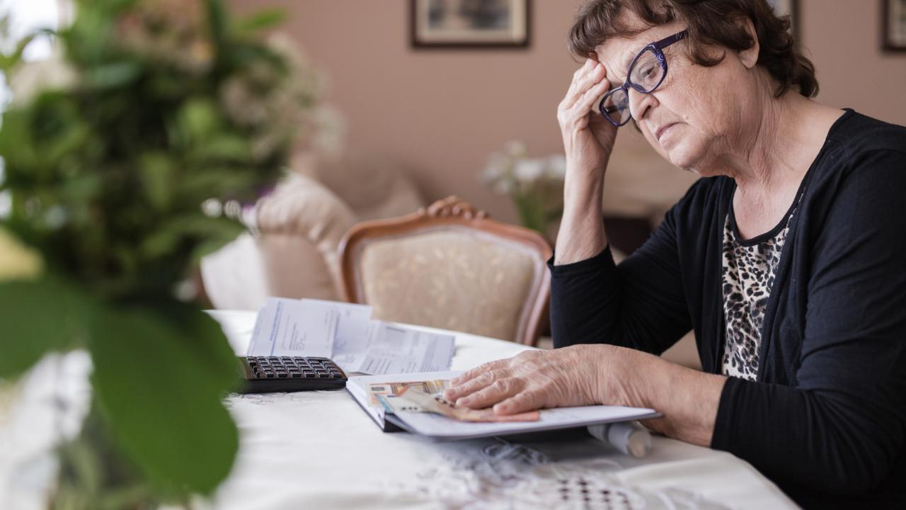 Woman sitting at dining table pondering bills