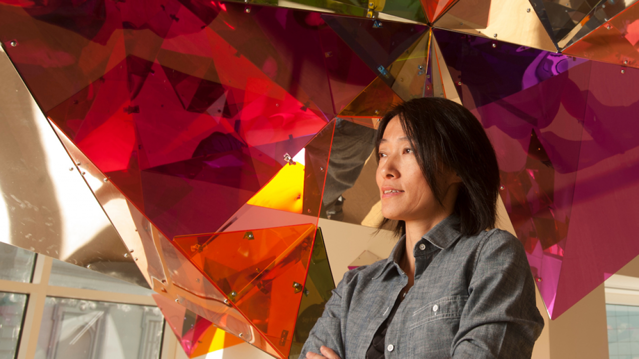 A women smiles in front of a colorful art installation