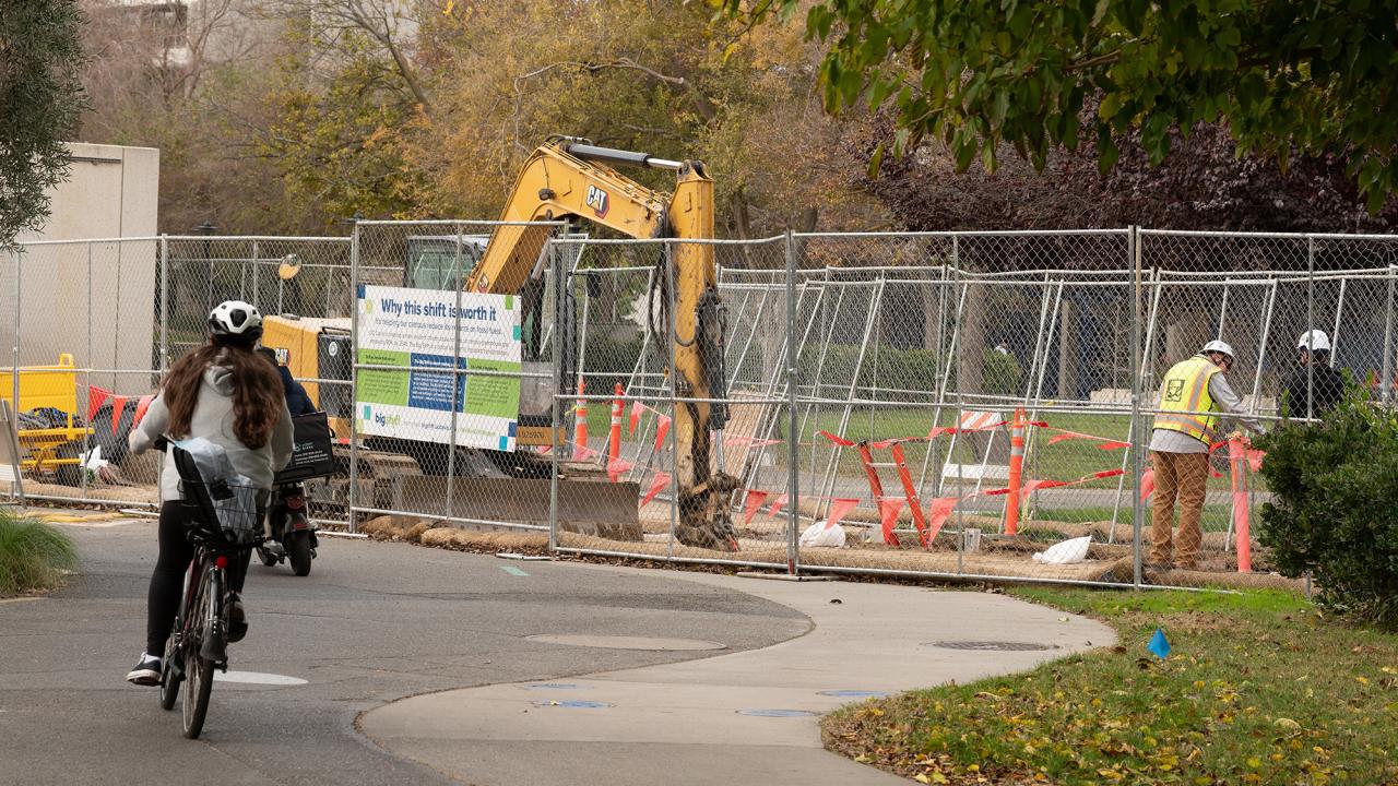 A cyclist rides in front of a construction site.