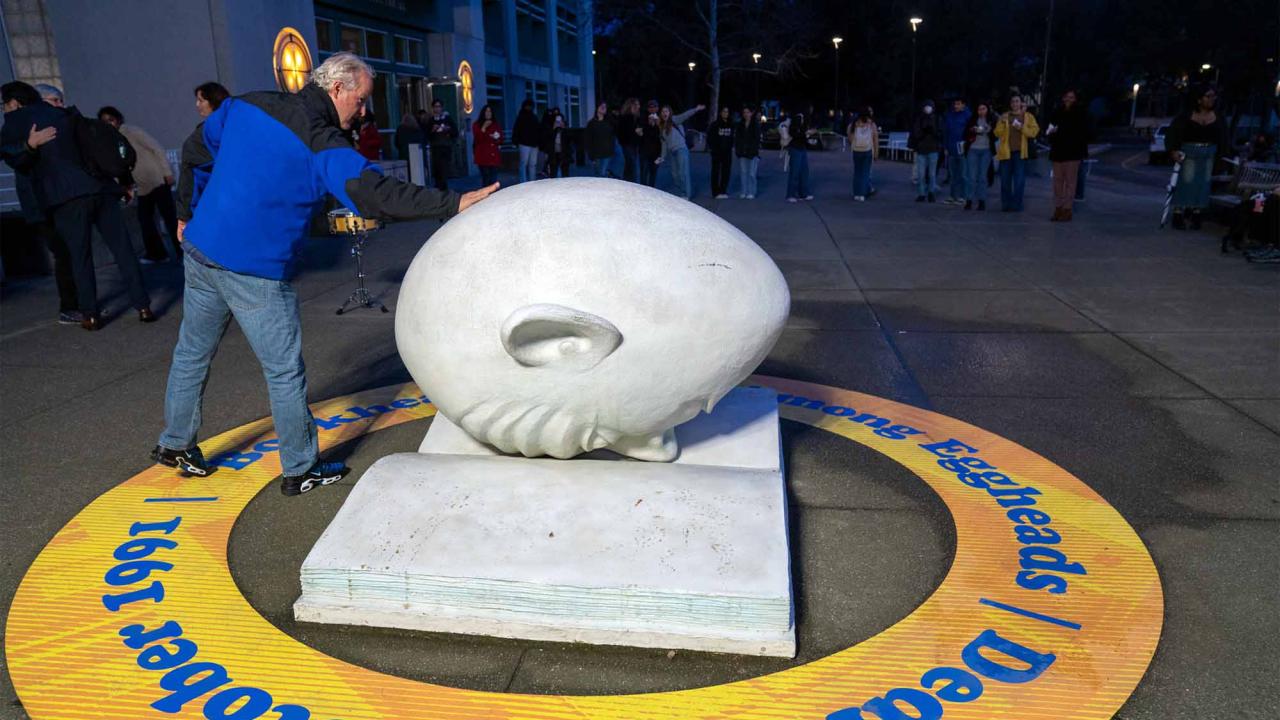 Kirk Arneson touches Bookhead sculpture