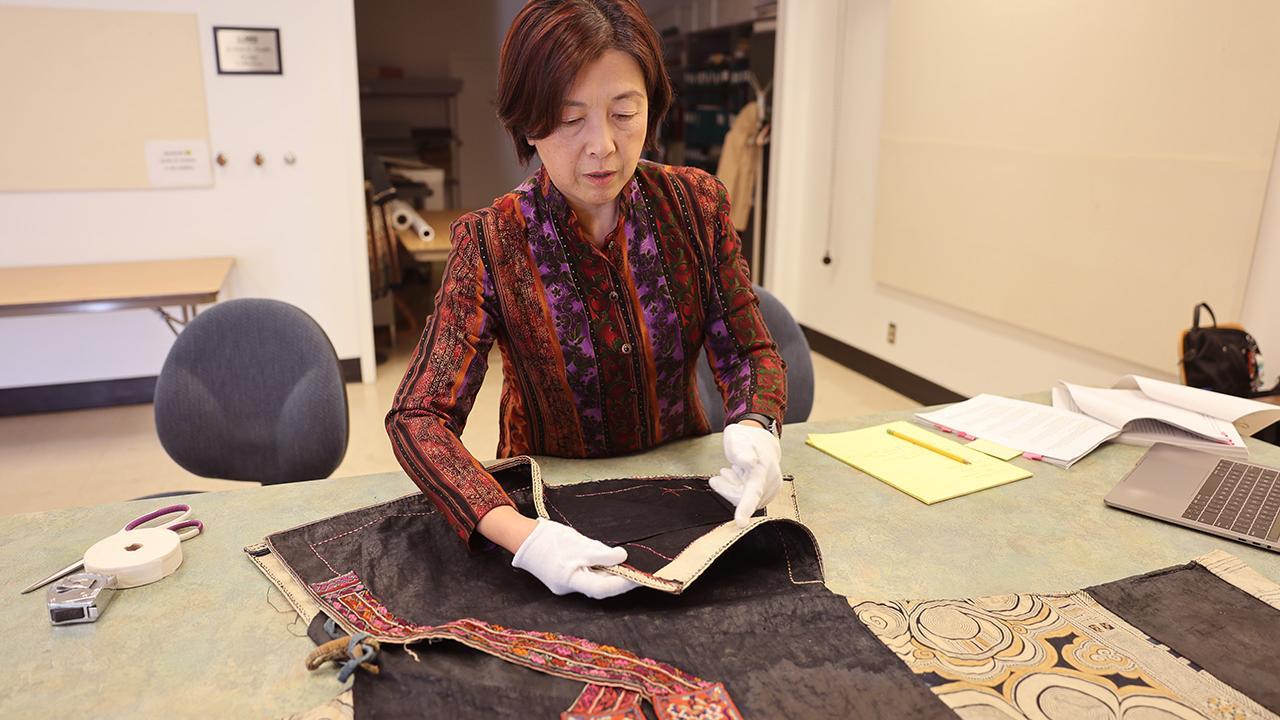 Adele Zhang, senior continuing lecturer, prepares a recently donated garment to be added to the Design Collection at UC Davis. (Maria Sestito/ UC Davis)