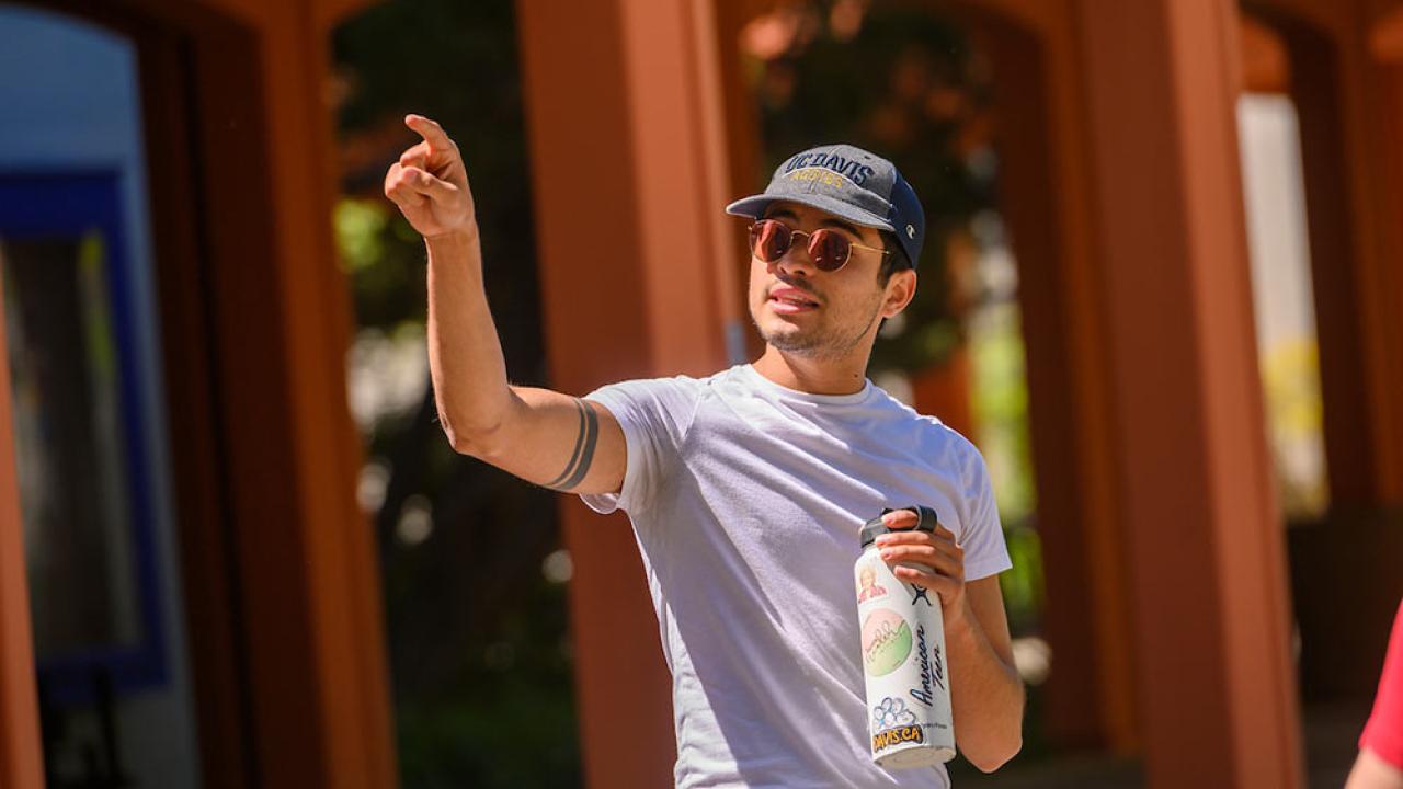 male tour guide pointing out a UC Davis campus landmark