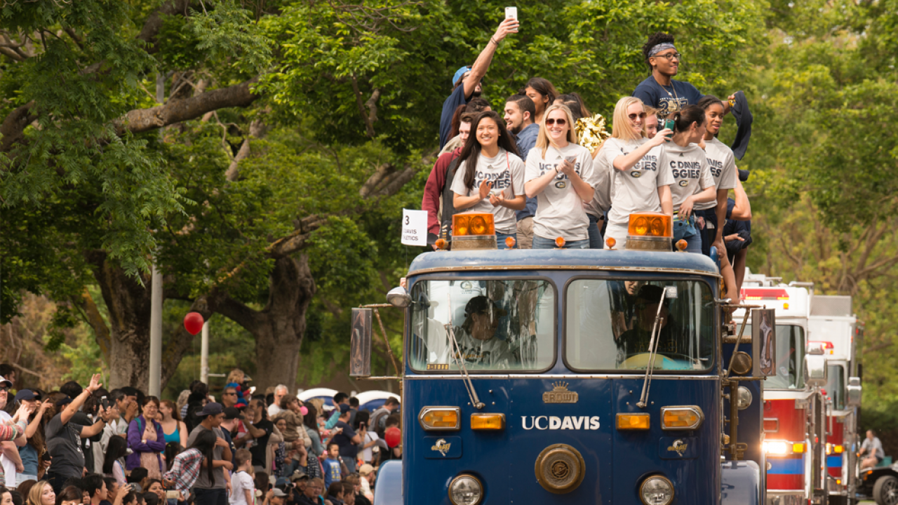 UC Davis students ride on top of a UC Davis branded blue fire engine during the picnic day parade