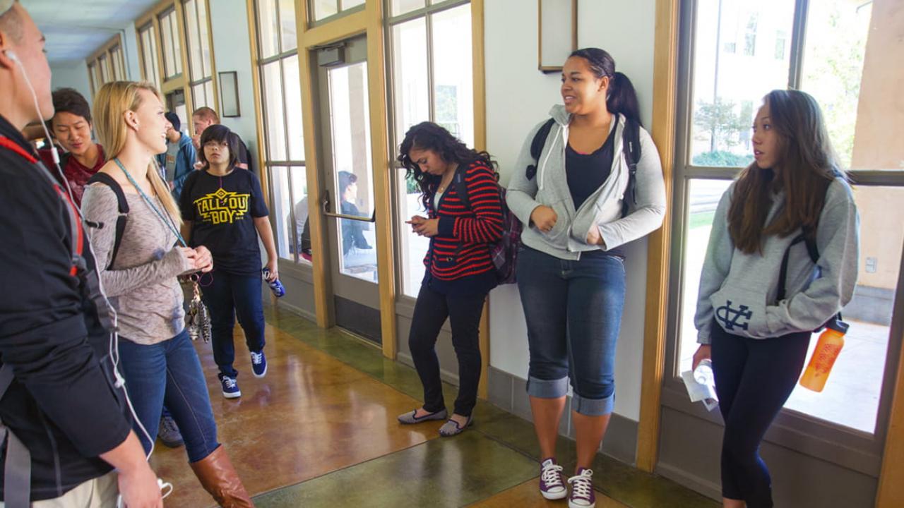 students gathering for a class and chatting in a hallway - transfer application timeline