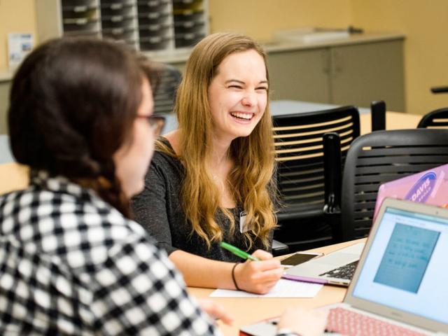 two students  work together on their laptops