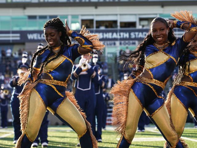 Members of the Majorettes dance group perform on the field during a football game