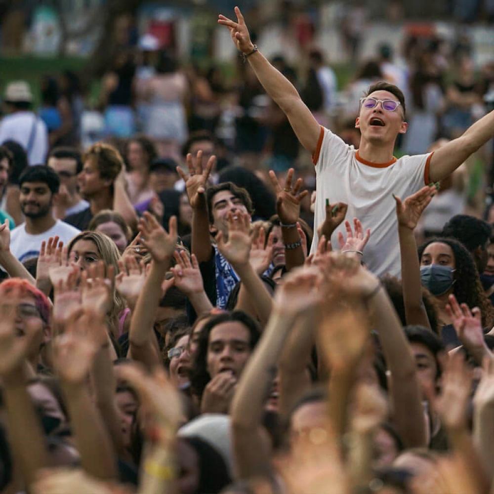 A student cheering above the crowd at the annual Lawntopia event on the Quad at UC Davis